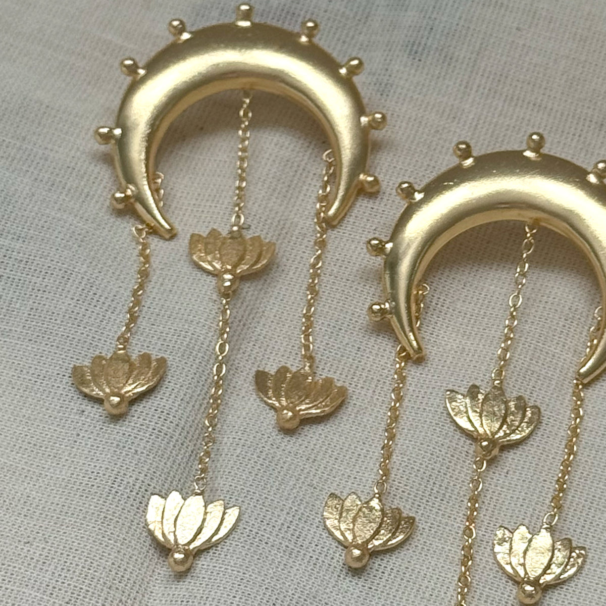 Close-up of Nilofer crescent earrings with cascading chains and lotus charms