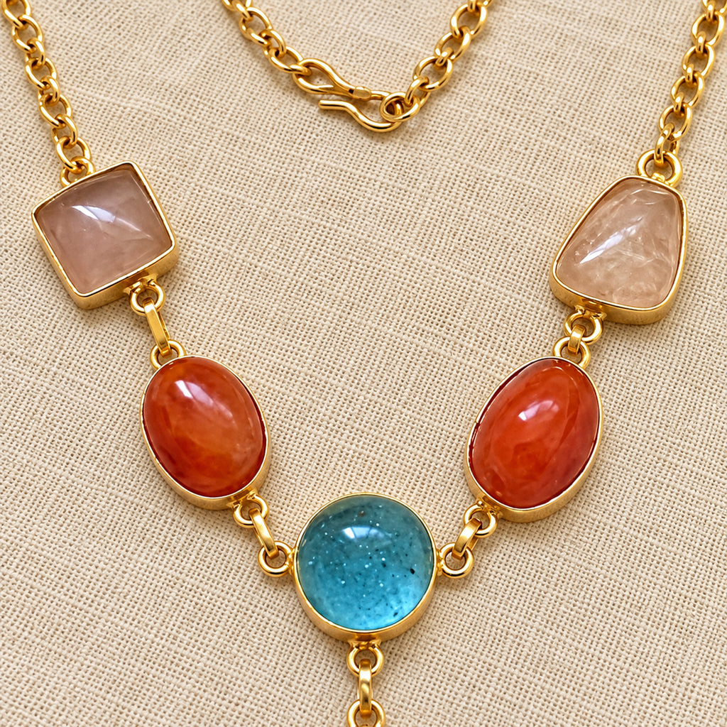 Close-up of gold-tone pendant necklace gemstones on neutral background