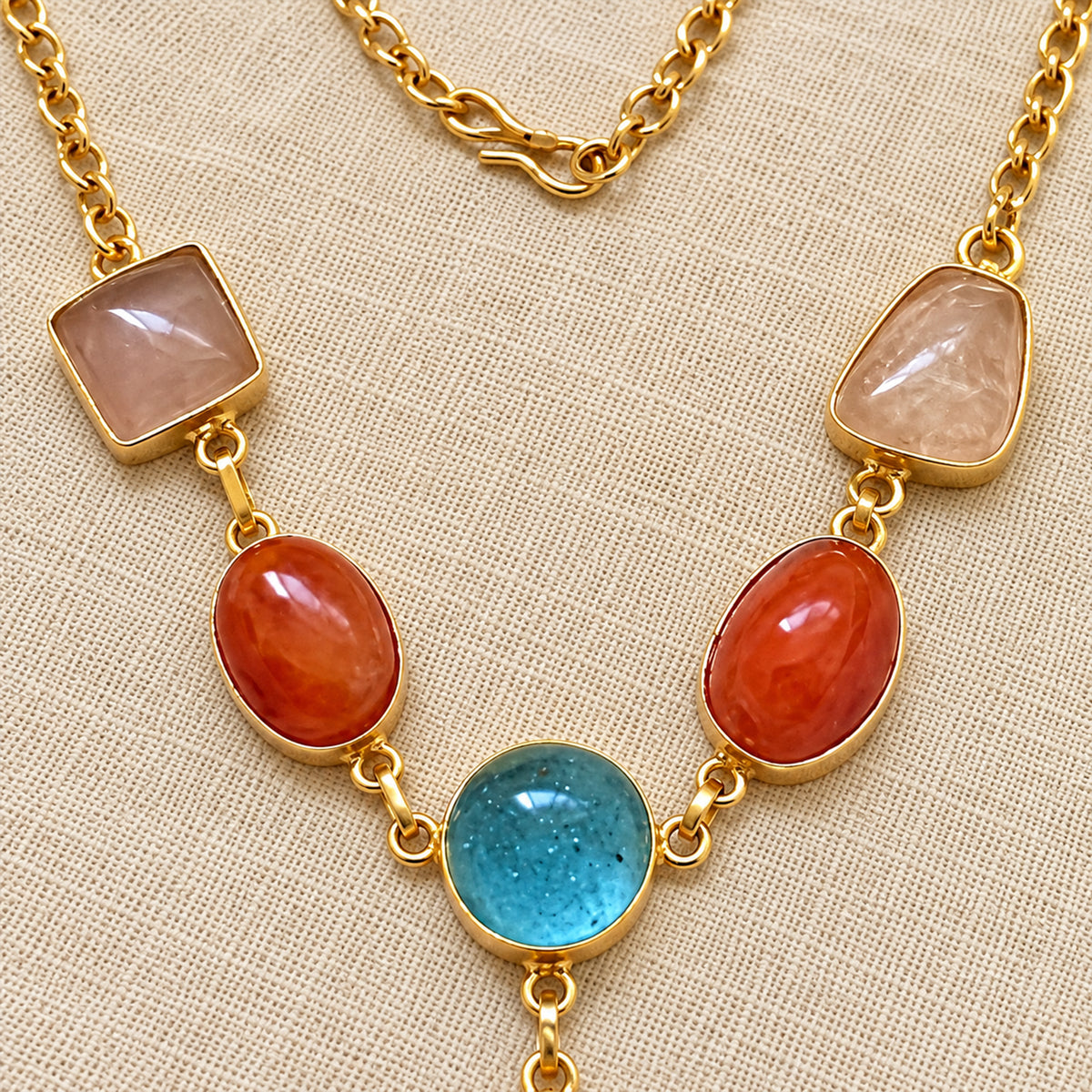 Close-up of gold-tone pendant necklace gemstones on neutral background
